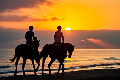 Balade à cheval sur une plage lors du coucher du soleil